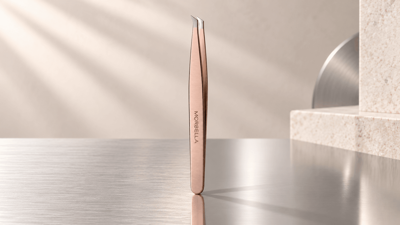 Morbella slant tweezers in a rose satin finish standing on brushed steel — cover for “Satin, mirror or matte? Choosing an instrument finish”